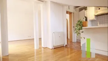 Helles Wohnzimmer mit Holzboden und offenem Übergang zu anderen Bereichen, ausgestattet mit Heizkörper.