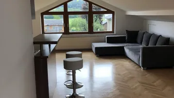 Helles Wohnzimmer im Dachgeschoss mit Holzboden, gemütlichem Sofa und Bartresen.