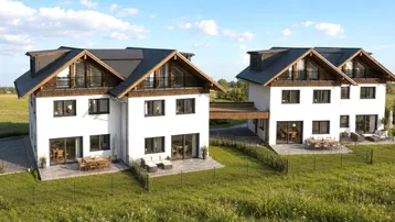 Moderne Doppelhäuser mit weißer Fassade und dunklen Dächern, eingebettet in eine grüne Landschaft.