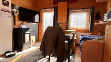 Rustikales Wohnzimmer in Holzbauweise mit Kaminofen und Blick ins Grüne.