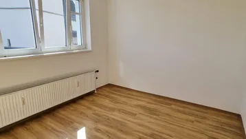 Helles, frisch renoviertes Zimmer mit Laminatboden und großem Fenster, bereit zur individuellen Gestaltung.