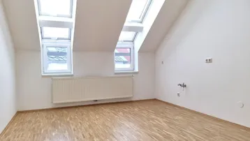 Geräumiges Dachzimmer mit viel Tageslicht durch mehrere Dach- und Giebelfenster.