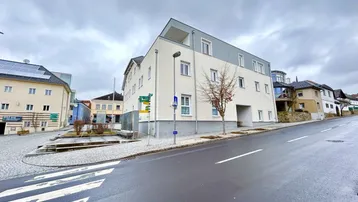 Modernes Mehrfamilienhaus mit heller Fassade und Flachdach an einer städtischen Straße gelegen.