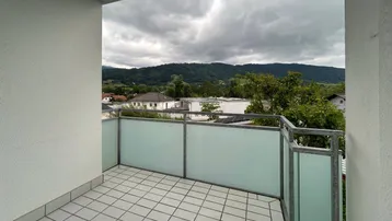 Balkon mit Fliesenboden und Blick auf die umliegende Berglandschaft und grüne Umgebung.