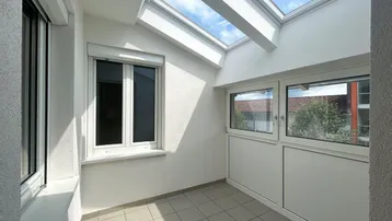 Heller, verglaster Balkon mit Fliesenboden und Dachfenstern, ideal als Wintergarten.