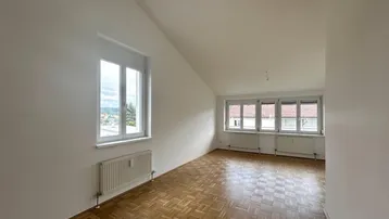 Helles Wohnzimmer mit Parkettboden, Dachschräge und weitem Ausblick auf die Umgebung.