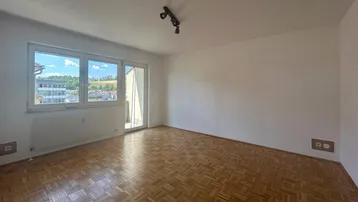 Helles Zimmer mit Parkettboden und Zugang zum Balkon, ideal als Wohn- oder Schlafzimmer.