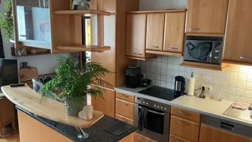 Moderne Küche mit hellen Holzfronten, Granitarbeitsplatte und integrierten Geräten.