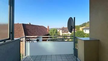 Sonniger Balkon mit Fliesenboden und Blick über die Dächer der Umgebung.