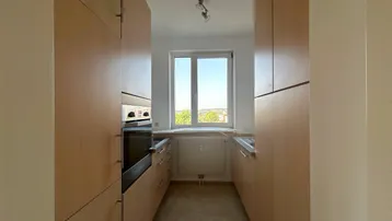 Funktionale Küche mit hellen Holzschränken, Einbauofen und Fenster mit Ausblick.