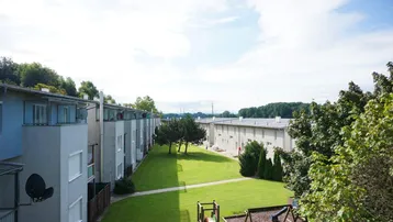 Blick auf die Wohnanlage mit großzügiger Grünfläche und Kinderspielplatz zwischen den Gebäuden.