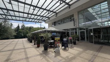 Außenbereich eines Restaurants mit großer Terrasse, Sonnenschirmen und Blick auf das Gebäude.