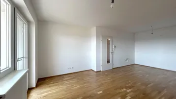 Helles, leeres Wohnzimmer mit Parkettboden und großen Fenstern, bereit zur individuellen Gestaltung.