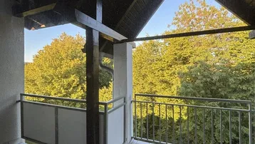 Überdachter Balkon mit Fliesenboden und einem schönen Blick ins Grüne.
