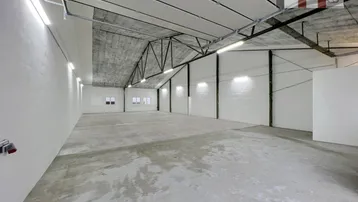 Geräumige, leere Lagerhalle mit hohen Decken, Betonboden und effizienter Beleuchtung.