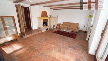 Geräumiges Wohnzimmer mit Kamin, Holzbalken und Terrakotta-Fliesenboden.