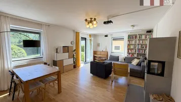 Helles Wohn- und Esszimmer mit Holzboden, Kamin und Zugang zum Garten.