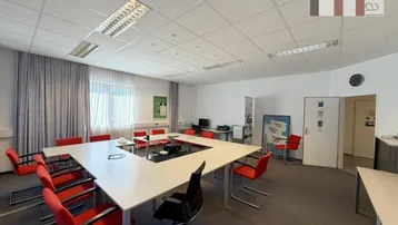 Großer Konferenzraum mit U-förmigem Tisch, vielen Stühlen und Teppichboden für Besprechungen.