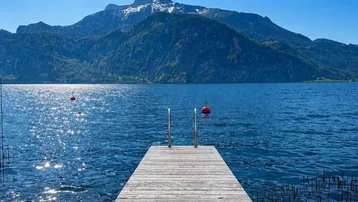 Holzsteg führt in den See mit majestätischem Bergblick unter strahlend blauem Himmel.