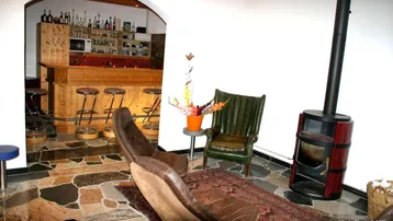 Gemütlicher Wohnbereich mit einer Holzbar, einem Kaminofen und bequemen Ledersesseln.