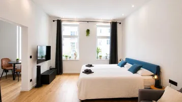 Helles Studio-Apartment mit Schlafbereich, Wohnbereich und Essgelegenheit auf Parkettboden.
