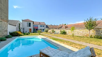 Großer Außenpool mit Liegestuhl und Blick auf das moderne Wohnhaus und den weitläufigen Garten.