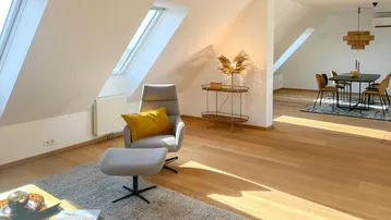 Lichtdurchfluteter Wohn- und Essbereich mit Dachschrägen, Holzboden und moderner Einrichtung.