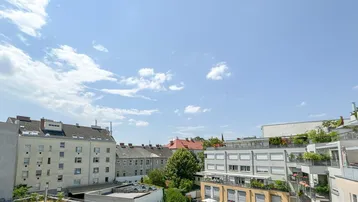 Panoramablick über die Dächer der Stadt mit grünen Innenhöfen und umliegenden Gebäuden.