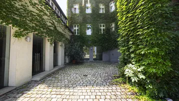 Innenhof mit Kopfsteinpflaster und einer von Efeu bewachsenen Gebäudefassade, die eine natürliche Ästhetik verleiht.