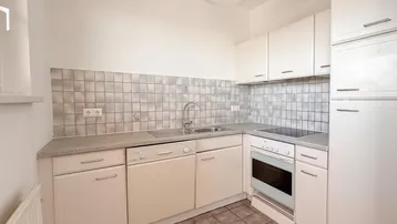 Funktionale Küche mit weißen Schränken, Fliesenboden und gefliestem Fliesenspiegel.