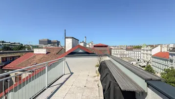 Geräumige Dachterrasse mit hellem Fliesenboden und weitem Blick über die Stadt.