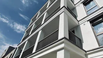 Moderne Architektur mit weißer Fassade und gestaffelten Balkonen unter blauem Himmel.