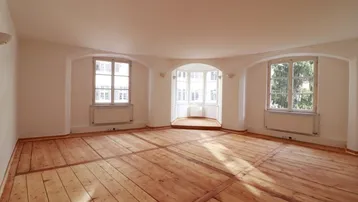 Geräumiges Wohnzimmer mit hellem Holzdielenboden und einem charmanten Erkerfenster, das viel Tageslicht hereinlässt.