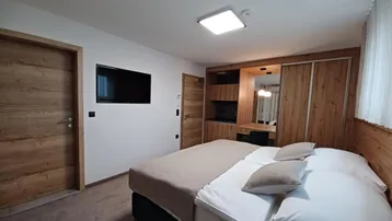 Modernes Schlafzimmer mit Doppelbett, integriertem Schrank und Fernseher an der Wand.