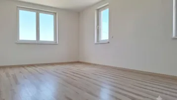 Heller, leerer Raum mit großen Fenstern und hellem Holzboden, ideal für individuelle Gestaltung.