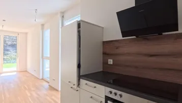 Moderne Küche mit integrierten Geräten, Kochfeld und Dunstabzugshaube, offen zum Wohnbereich.