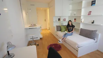 Helles Schlafzimmer mit Einzelbett, Schreibtisch und integrierten Regalen in modernem Stil.
