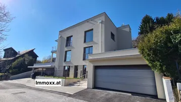 Modernes Gebäude mit klarer Architektur, großen Fenstern und integrierter Garage.