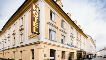 Historisches Hotelgebäude an einer Straßenecke mit gelber Fassade und traditioneller Architektur.
