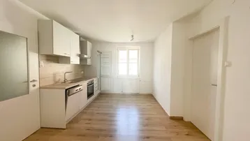 Helle, moderne Küche mit Holzboden und integrierten Geräten in einem offenen Wohnbereich.
