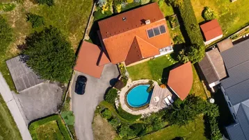 Luftaufnahme des Anwesens mit Haus, Garten, Pool und umliegender grüner Landschaft.