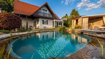 Charmantes Einfamilienhaus mit großem Naturpool und gemütlicher Pergola im gepflegten Gartenbereich.
