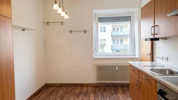 Helle Küche mit Holzschränken, Laminatboden und Blick auf die gegenüberliegenden Balkone.