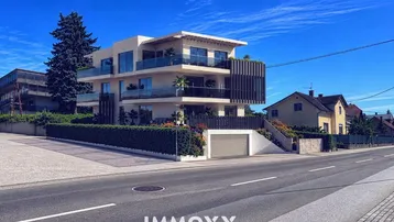 Moderne Wohnanlage mit mehreren Balkonen und Tiefgaragenzufahrt von der Straße aus.