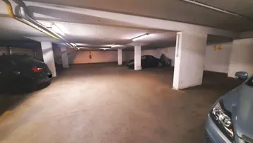 Geräumige Tiefgarage mit Betonboden und mehreren Stellplätzen, gut beleuchtet und funktional.