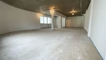 Großer, unfertiger Raum mit Beton-Decke und hellen Bodenfliesen, bereit für den Ausbau mit viel Tageslicht.