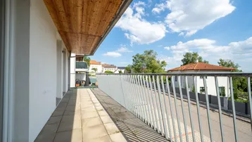 Langer Balkon mit Fliesenboden und Holzdecke, bietet einen weiten Blick auf die Umgebung.