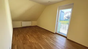 Helles Schlafzimmer mit Holzboden, gelben Wänden und Zugang zu einem französischen Balkon.