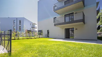 Moderne Wohnanlage mit großzügiger Rasenfläche und privater Terrasse im Erdgeschoss.