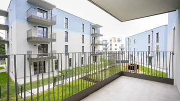 Balkon mit Blick auf den begrünten Innenhof und moderne Wohngebäude der Anlage.